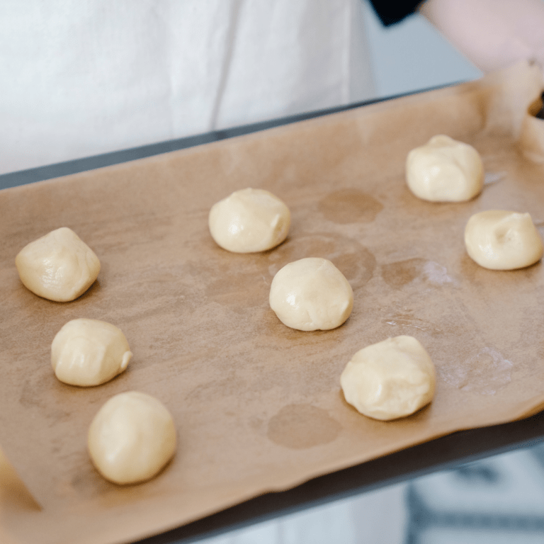 Teigkugeln auf Backblech mit Backpapier ausgelegt